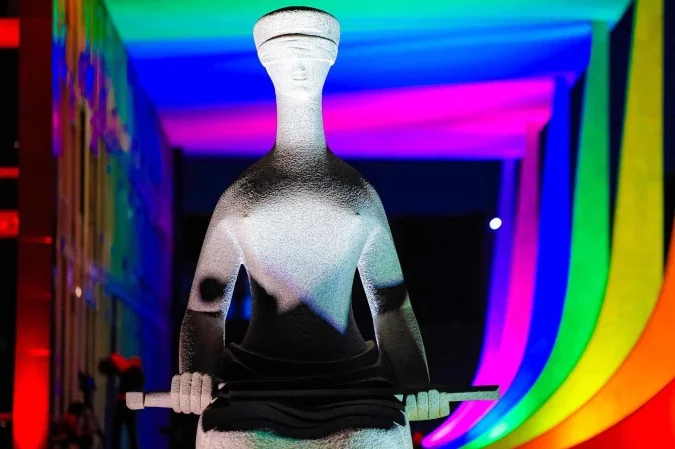Estátua da Justiça em frente ao prédio do Supremo Tribunal Federal (STF), iluminada com as cores do arco-íris em homenagem ao mês do Orgulho LGBTQIAPN+.